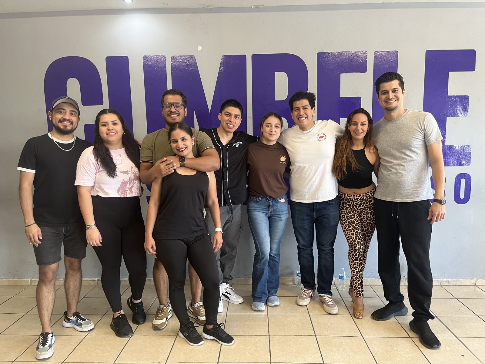 Alumnos de Cumbele sonriendo frente al logo de la escuela
